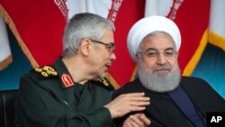 TT Iran Hassan Rouhani, bên phải, lắng nghe Tướng Mohammad Hossein Benghari, Chủ tịch ban Tham mưu trưởng các Lực lượng Iran, trong một cuộc diễu hành quân sự vào ngày 18/4/2019. (Iranian Presidency Office via AP)